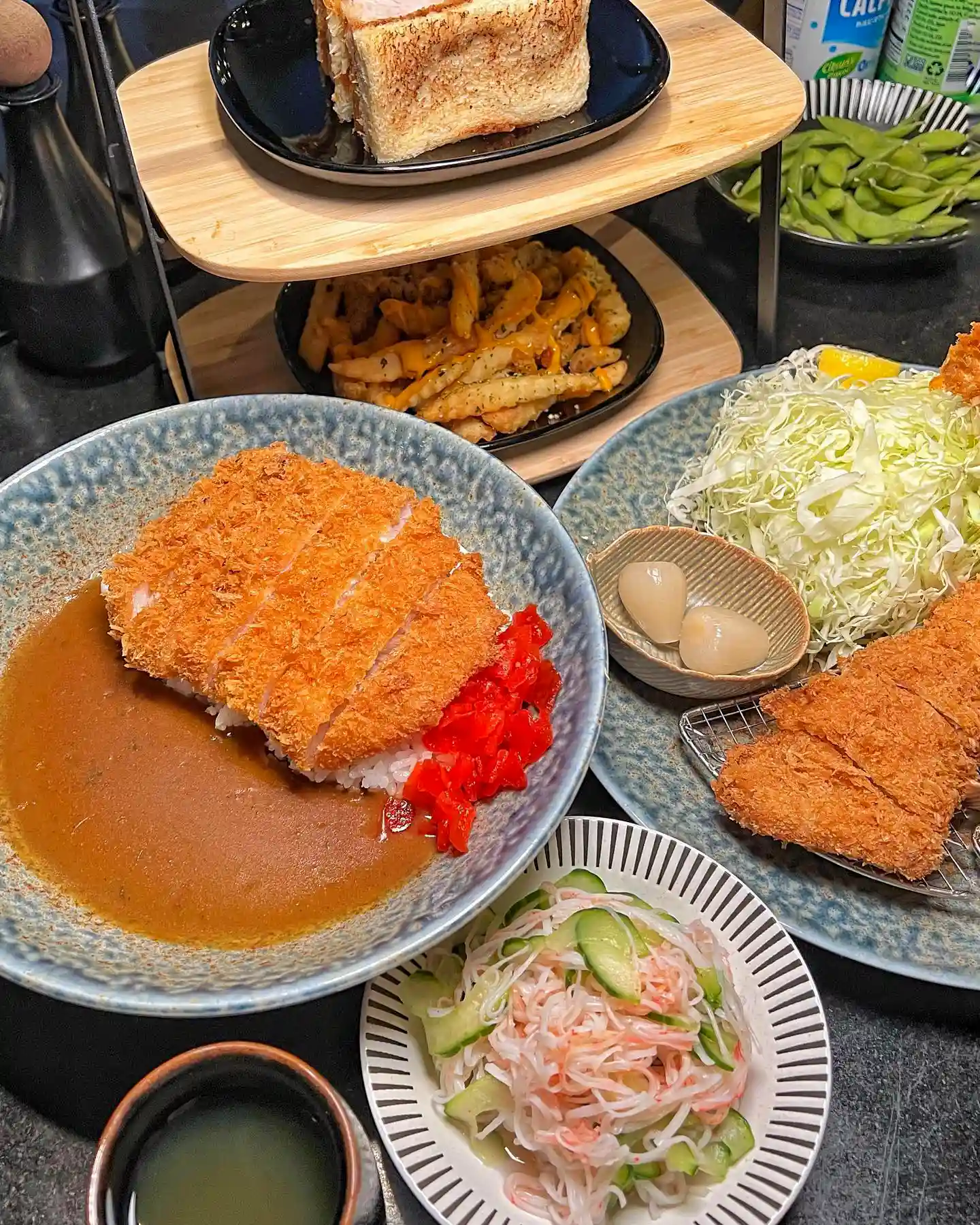 Assorted dishes from Kiyoshi's Katsu House, including tonkatsu, katsu curry, and french fries, beautifully plated and garnished