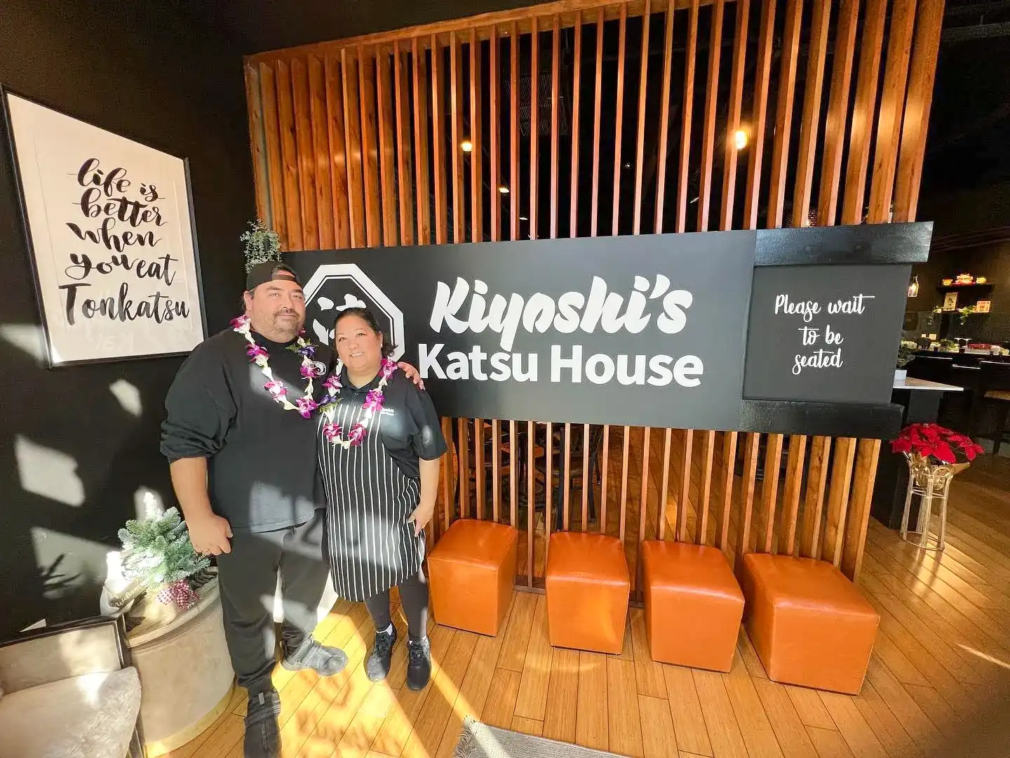 Mark and Beth, the owners of Kiyoshi's Katsu House, standing together in the entrance of their restaurant, smiling and welcoming guests